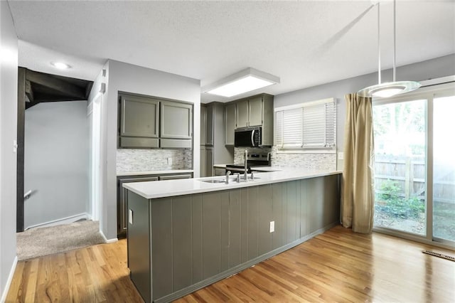 10981 Rosehill Rd, Overland Park, KS 66210 - kitchen featuring stainless steel appliances, a peninsula, decorative backsplash, light wood-type flooring, and light countertops