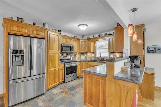 203 Pine St, Wellsville, KS 66092 - kitchen with stainless steel appliances, a peninsula, dark countertops, tasteful backsplash, and hanging light fixtures