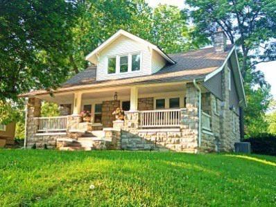 view of front facade featuring covered porch, a front lawn, and a chimney