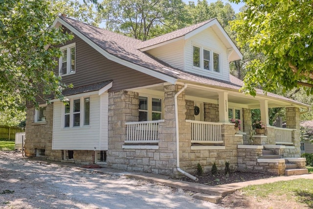 craftsman house with stone siding, a porch, and roof with shingles