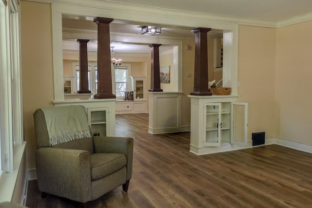 sitting room with decorative columns, crown molding, dark wood-style flooring, a chandelier, and baseboards