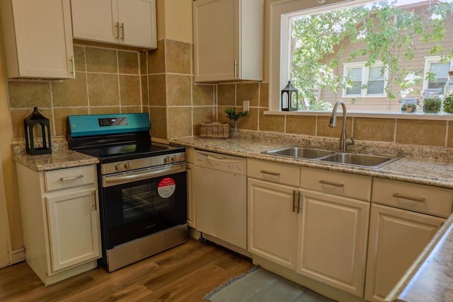 kitchen with white dishwasher, electric stove, a sink, wood finished floors, and tasteful backsplash