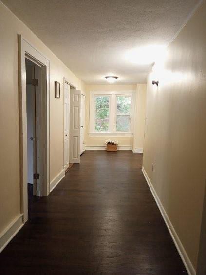 hall featuring dark wood-style floors, baseboards, and a textured ceiling