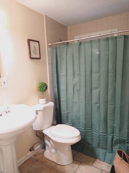 bathroom featuring tile patterned floors, a shower with shower curtain, and toilet