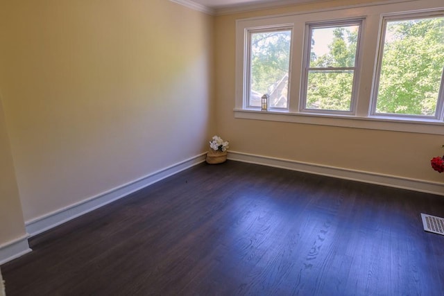 empty room featuring ornamental molding, dark wood-style floors, and baseboards