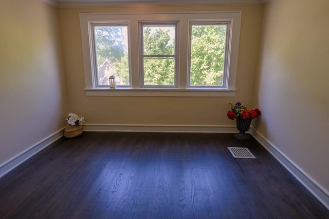 empty room featuring ornamental molding, dark wood finished floors, and baseboards