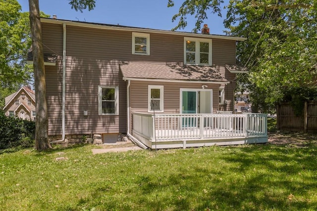 rear view of property with a wooden deck, a chimney, and a lawn
