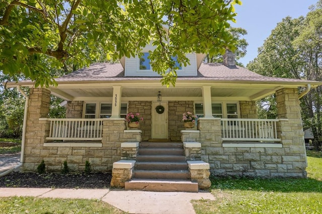 1515 E 77th Ter, Kansas City, MO 64131 - view of front of house featuring covered porch, stone siding, a chimney, and roof with shingles