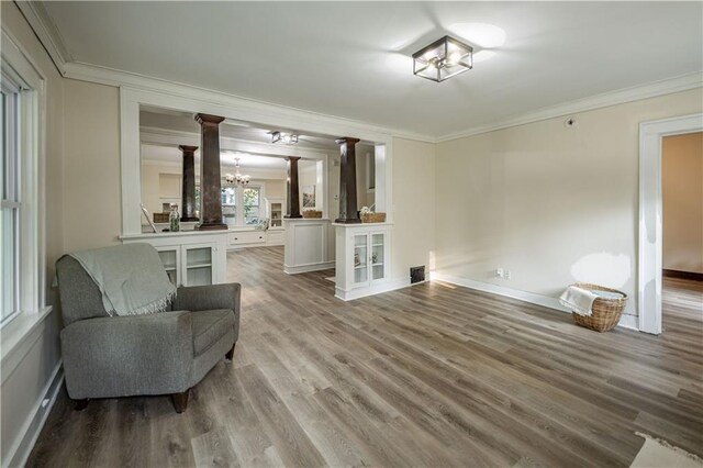 1515 E 77th Ter, Kansas City, MO 64131 - living area featuring crown molding, ornate columns, a chandelier, and wood finished floors