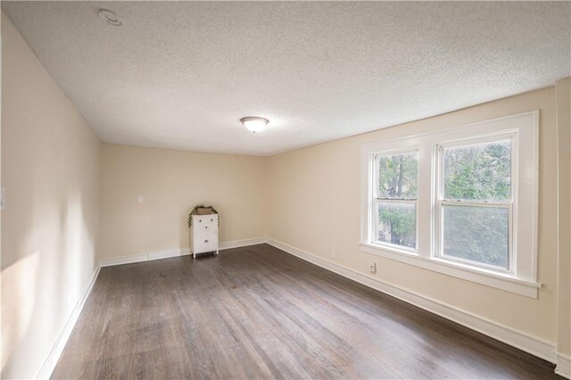 1515 E 77th Ter, Kansas City, MO 64131 - empty room with dark wood finished floors and a textured ceiling