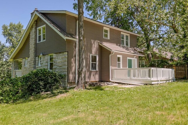 1515 E 77th Ter, Kansas City, MO 64131 - rear view of house featuring a wooden deck, stone siding, and roof with shingles