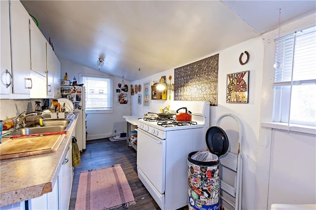 kitchen featuring white range with gas stovetop, a sink, lofted ceiling, white cabinets, and light countertops