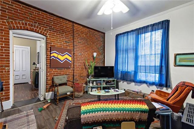 living area with wood finished floors, brick wall, and ceiling fan