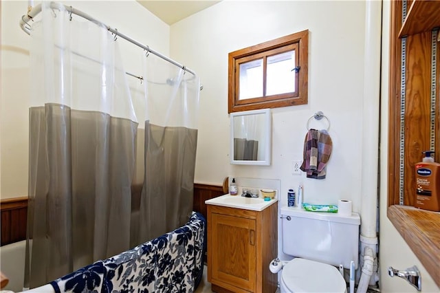 full bathroom with wainscoting, curtained shower, vanity, and toilet