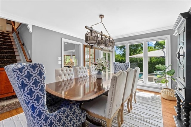 dining area featuring light wood-style floors, a chandelier, ornamental molding, and stairway