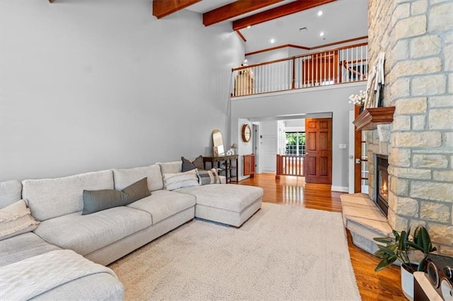living room with wood finished floors, a high ceiling, a fireplace, beamed ceiling, and recessed lighting