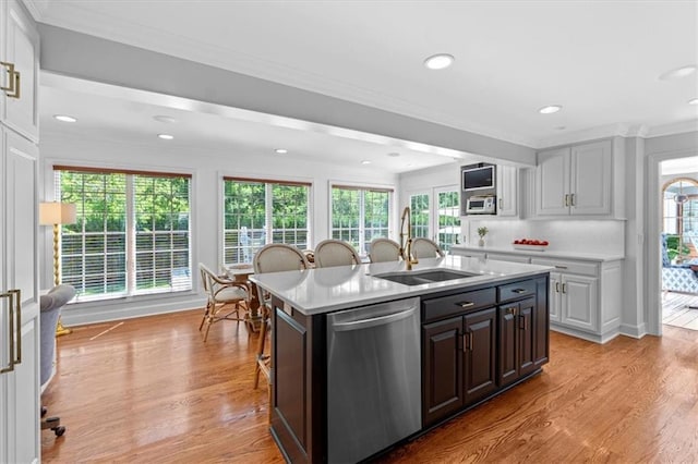 kitchen featuring dishwasher, crown molding, a sink, light countertops, and light wood-type flooring