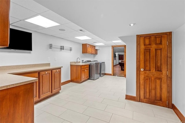 kitchen featuring baseboards, brown cabinets, light countertops, and a sink