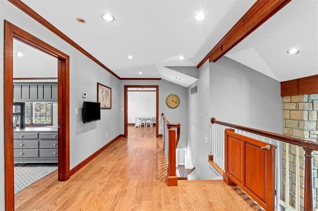 hallway with an upstairs landing, light wood finished floors, recessed lighting, baseboards, and ornamental molding