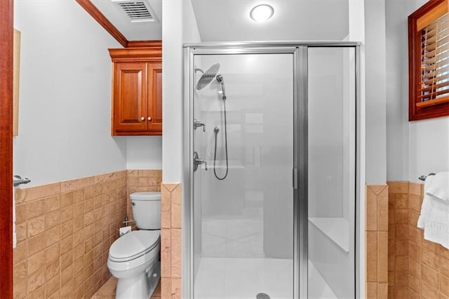 full bathroom featuring tile walls, a stall shower, toilet, a wainscoted wall, and tile patterned flooring