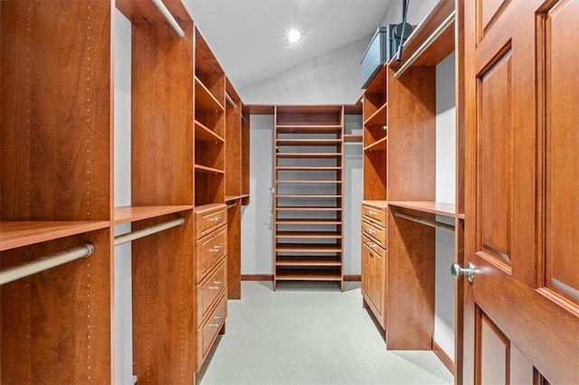 walk in closet with light carpet and vaulted ceiling