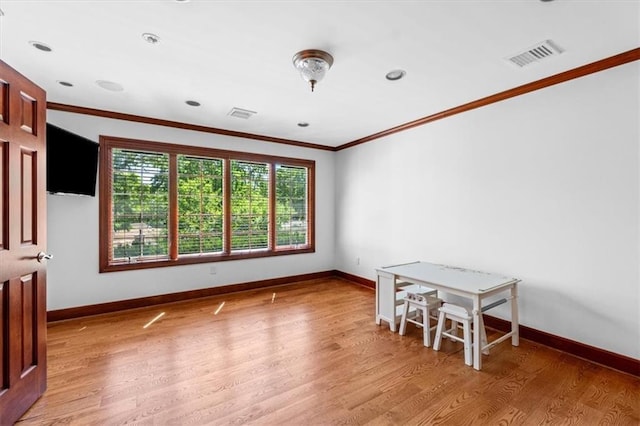 empty room featuring crown molding, light wood-style floors, and baseboards