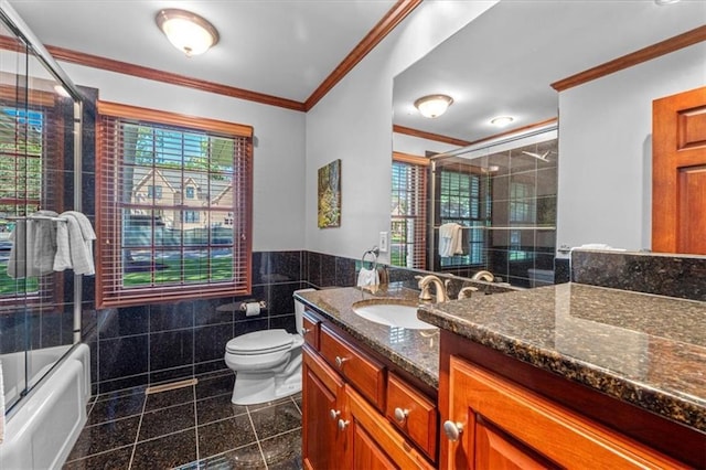 full bath featuring tile walls, vanity, toilet, wainscoting, and crown molding