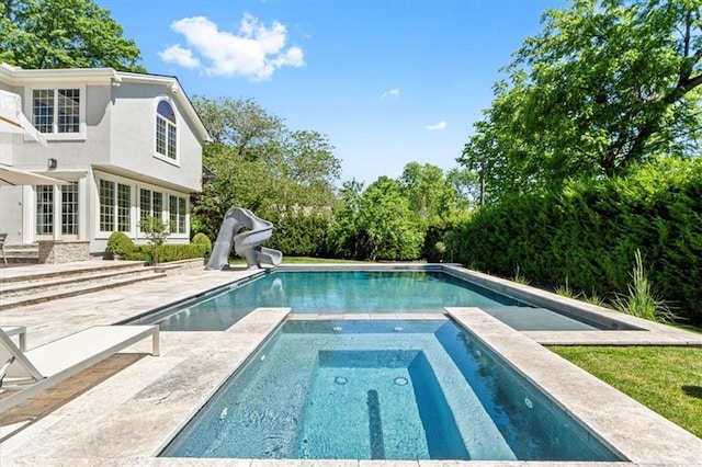 view of swimming pool featuring a water slide, a patio, and a pool with connected hot tub