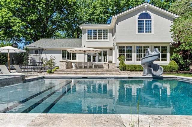 outdoor pool featuring a water slide and a patio area