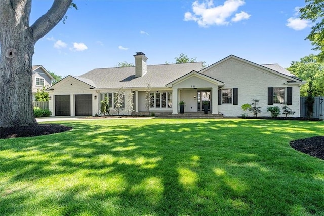 back of property featuring an attached garage, a chimney, and driveway