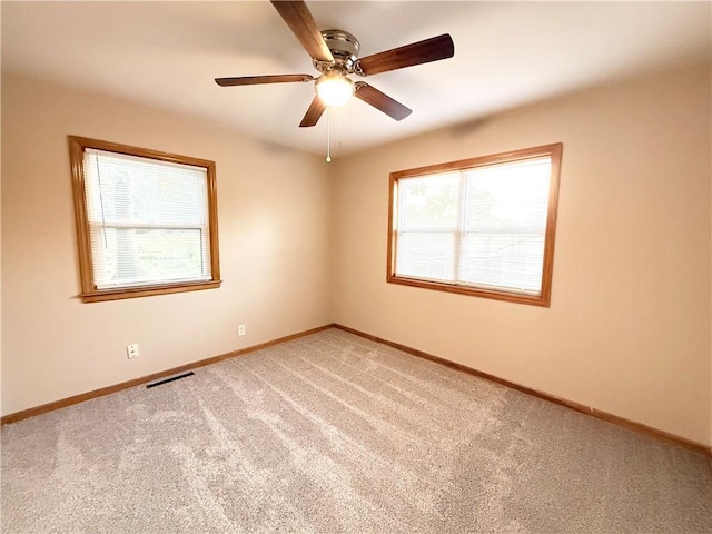 carpeted spare room featuring baseboards and a ceiling fan