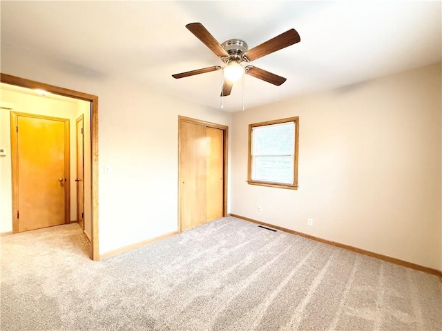 unfurnished bedroom featuring carpet flooring, a closet, baseboards, and a ceiling fan