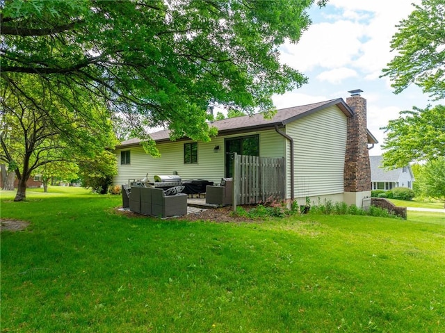 rear view of house featuring an outdoor living space, a chimney, and a lawn
