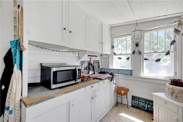 827 Pacific Ave, Osawatomie, KS 66064 - kitchen featuring stainless steel microwave, white cabinets, light tile patterned floors, light countertops, and wooden ceiling