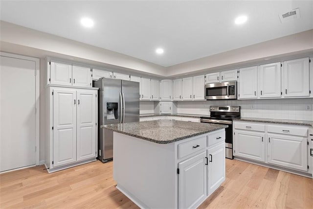 1051 E 121st St, Olathe, KS 66061 - kitchen with stainless steel appliances, a kitchen island, dark stone countertops, light wood-type flooring, and recessed lighting