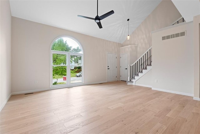 1051 E 121st St, Olathe, KS 66061 - unfurnished living room with ceiling fan, stairs, light wood-style floors, high vaulted ceiling, and baseboards