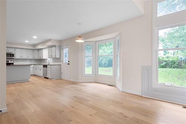 1051 E 121st St, Olathe, KS 66061 - kitchen featuring stainless steel appliances, light wood finished floors, baseboards, a sink, and pendant lighting