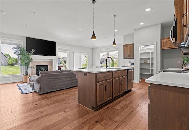 1532 SW Arbor Valley Dr, Lees Summit, MO 64082 - kitchen with a sink, appliances with stainless steel finishes, a fireplace, a center island with sink, and light countertops