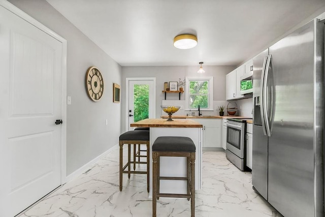 9811 Cambridge Ave, Kansas City, MO 64134 - kitchen with stainless steel appliances, wooden counters, a sink, and light marble finish flooring