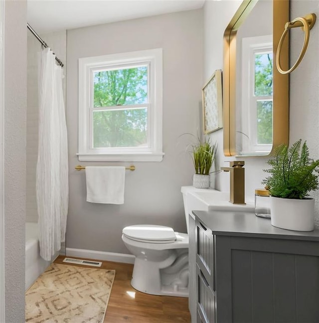 9811 Cambridge Ave, Kansas City, MO 64134 - full bath featuring toilet, wood finished floors, vanity, shower / tub combo with curtain, and baseboards
