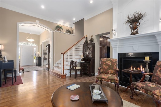 4704 SW Gull Point Dr, Lees Summit, MO 64082 - living area featuring wood finished floors, arched walkways, a tiled fireplace, stairs, and baseboards