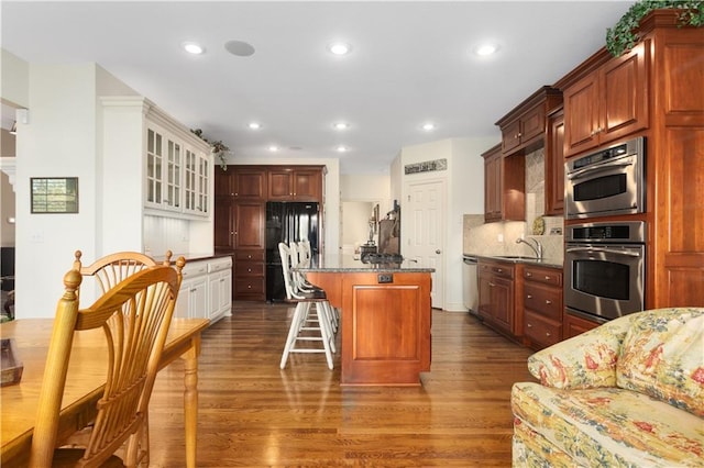 4704 SW Gull Point Dr, Lees Summit, MO 64082 - kitchen with stainless steel appliances, dark wood finished floors, a center island, dark stone countertops, and tasteful backsplash