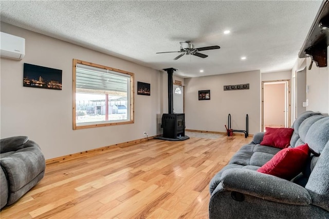 6721 S Read Rd Unit 1, Pleasanton, KS 66075 - living room featuring a wood stove, light wood-type flooring, a ceiling fan, an AC wall unit, and recessed lighting