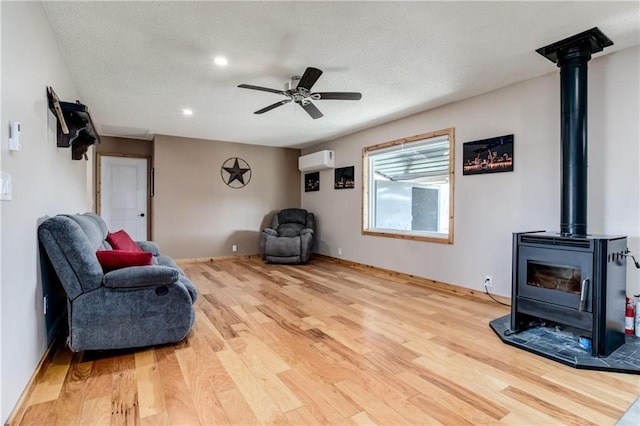 6721 S Read Rd Unit 1, Pleasanton, KS 66075 - sitting room featuring an AC wall unit, a wood stove, wood finished floors, a ceiling fan, and recessed lighting