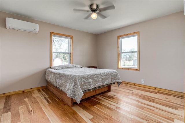 6721 S Read Rd Unit 1, Pleasanton, KS 66075 - bedroom featuring a wall mounted AC, light wood-type flooring, baseboards, and ceiling fan