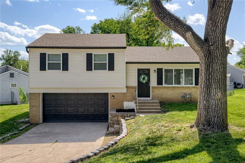 3200 Queen Ridge Dr, Independence, MO 64055 - tri-level home with brick siding, a front yard, an attached garage, and concrete driveway