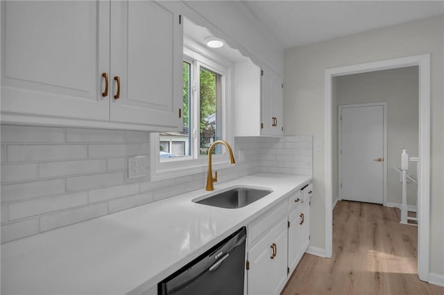14 Woodbridge Ln, Kansas City, MO 64145 - kitchen featuring black dishwasher, a sink, white cabinetry, light countertops, and light wood finished floors