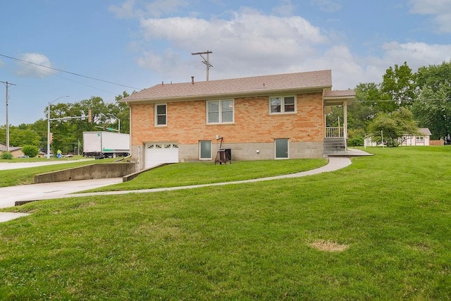 911 Limit St, Leavenworth, KS 66048 - back of house with driveway, an attached garage, brick siding, and a lawn