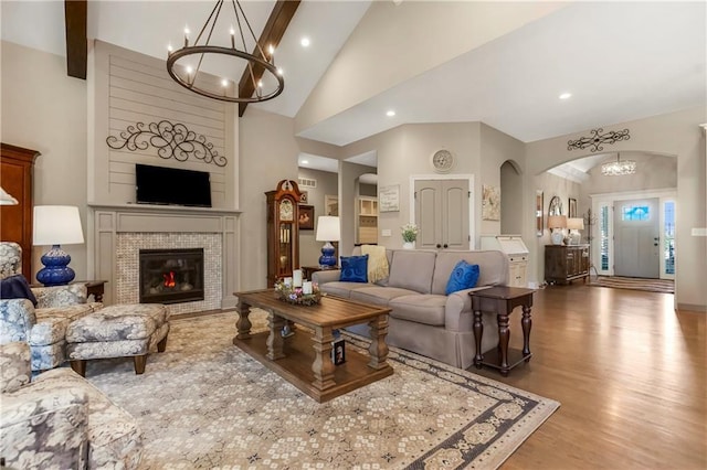living room featuring a chandelier, wood finished floors, arched walkways, recessed lighting, and a fireplace