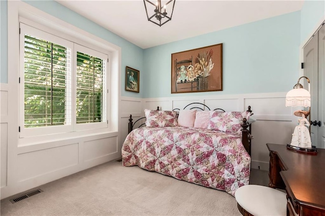 bedroom featuring a decorative wall, carpet floors, multiple windows, and wainscoting